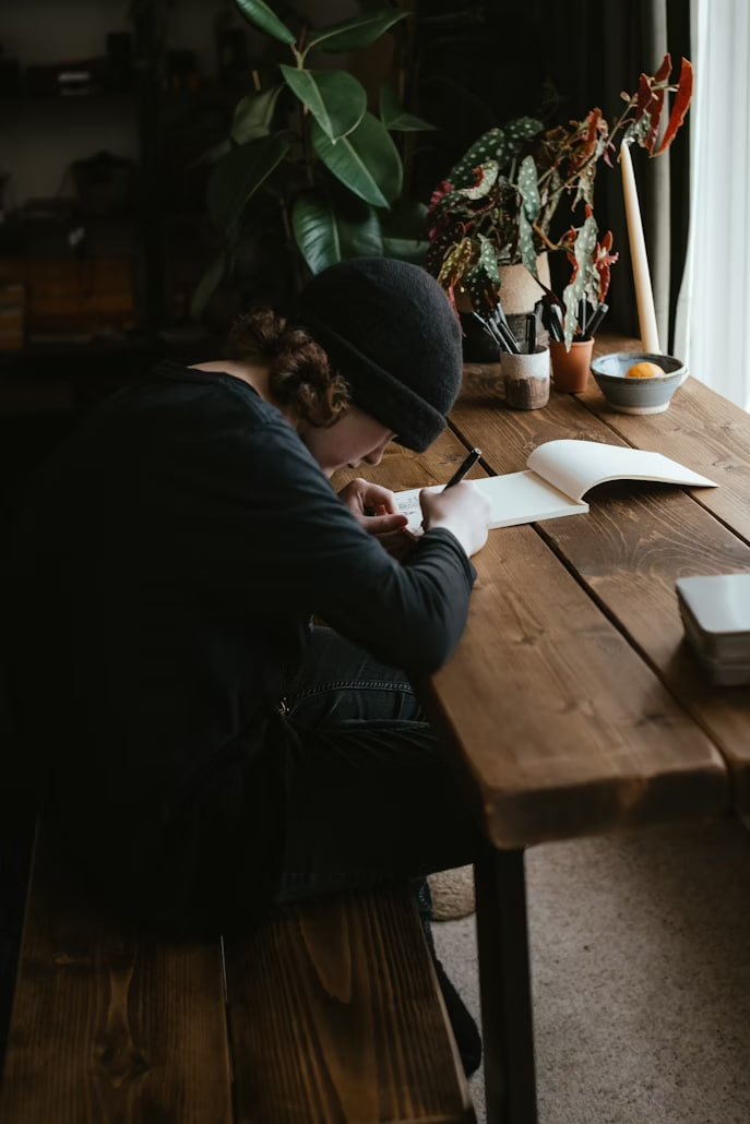 Penulis sedang merevisi naskah buku di depan laptop dengan catatan dan kopi