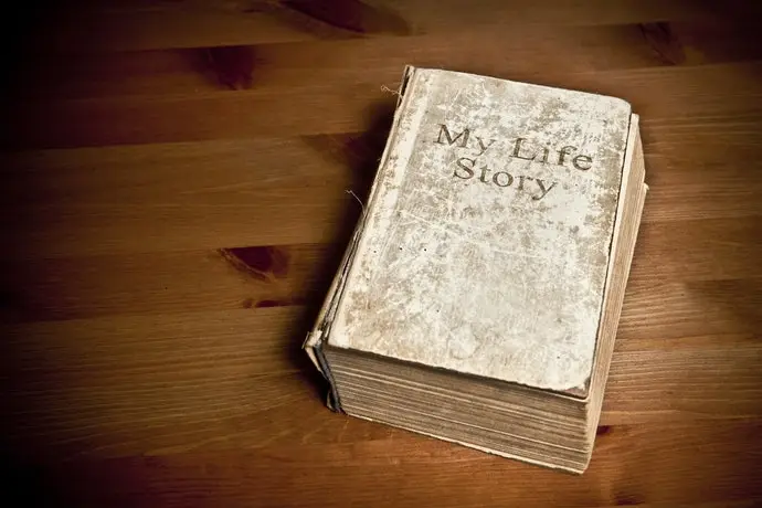 Penulis sedang menulis buku memoar di meja kerja